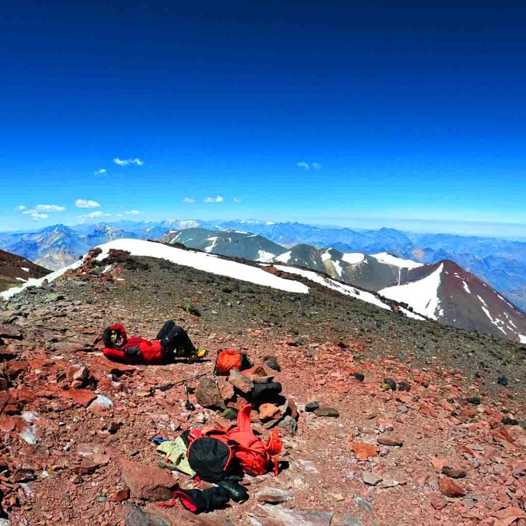 Vista de las piernas y botas del hombre sobre una roca en la cima de la  montaña con vistas a un valle
